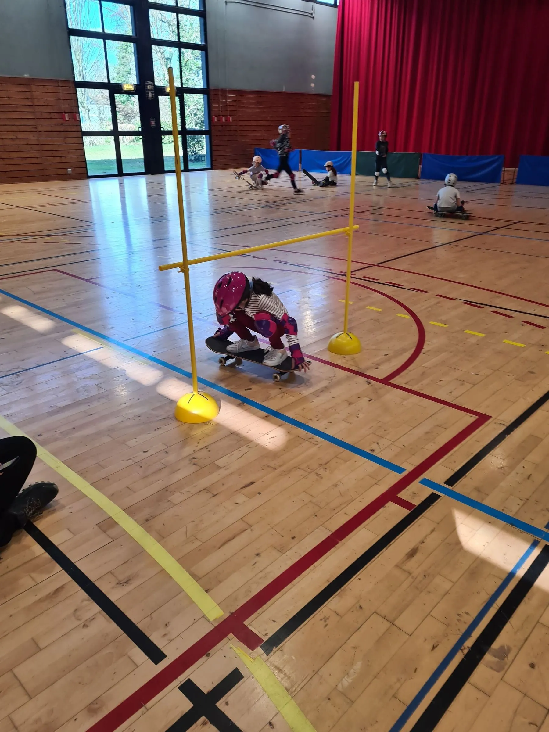 Un groupe d’enfants en protections apprend le skate avec le moniteur